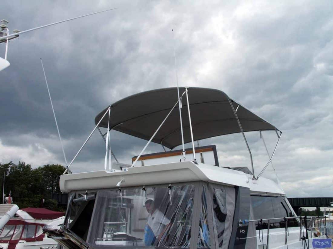 Sealine F42 bimini with a curved design, featuring Sunbrella fabric and stainless steel frame for flybridge protection.