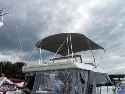 Sealine F42 bimini with a curved design, featuring Sunbrella fabric and stainless steel frame for flybridge protection.