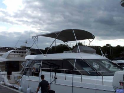 Sealine F42 bimini with a curved design, featuring Sunbrella fabric and stainless steel frame for flybridge protection.