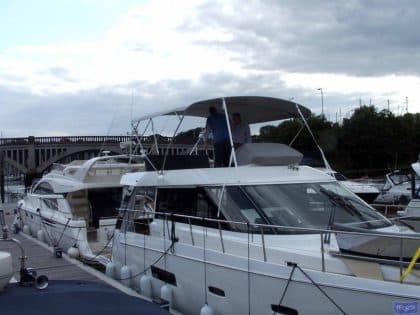 Sealine F42 bimini with a curved design, featuring Sunbrella fabric and stainless steel frame for flybridge protection.