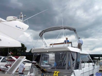 Sealine F42 bimini with a curved design, featuring Sunbrella fabric and stainless steel frame for flybridge protection.