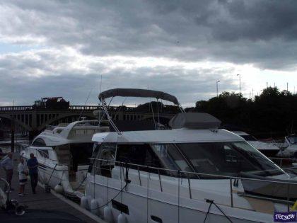 Sealine F42 bimini with a curved design, featuring Sunbrella fabric and stainless steel frame for flybridge protection.