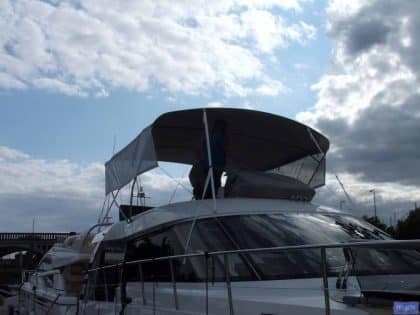 Sealine F42 bimini with a curved design, featuring Sunbrella fabric and stainless steel frame for flybridge protection.